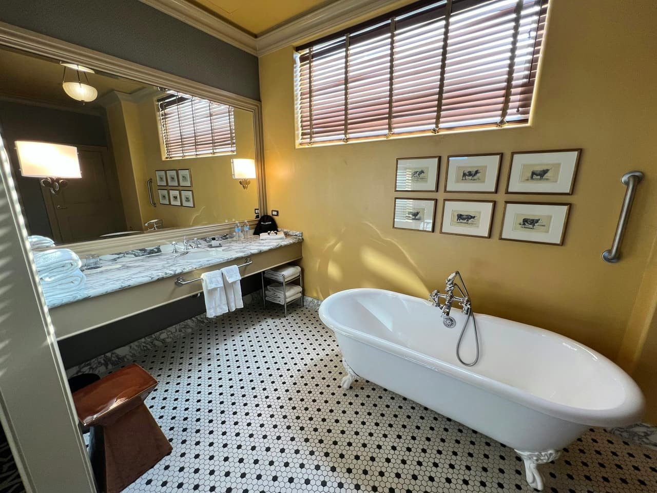 A bathroom with a basin, a wide mirror and framed prints