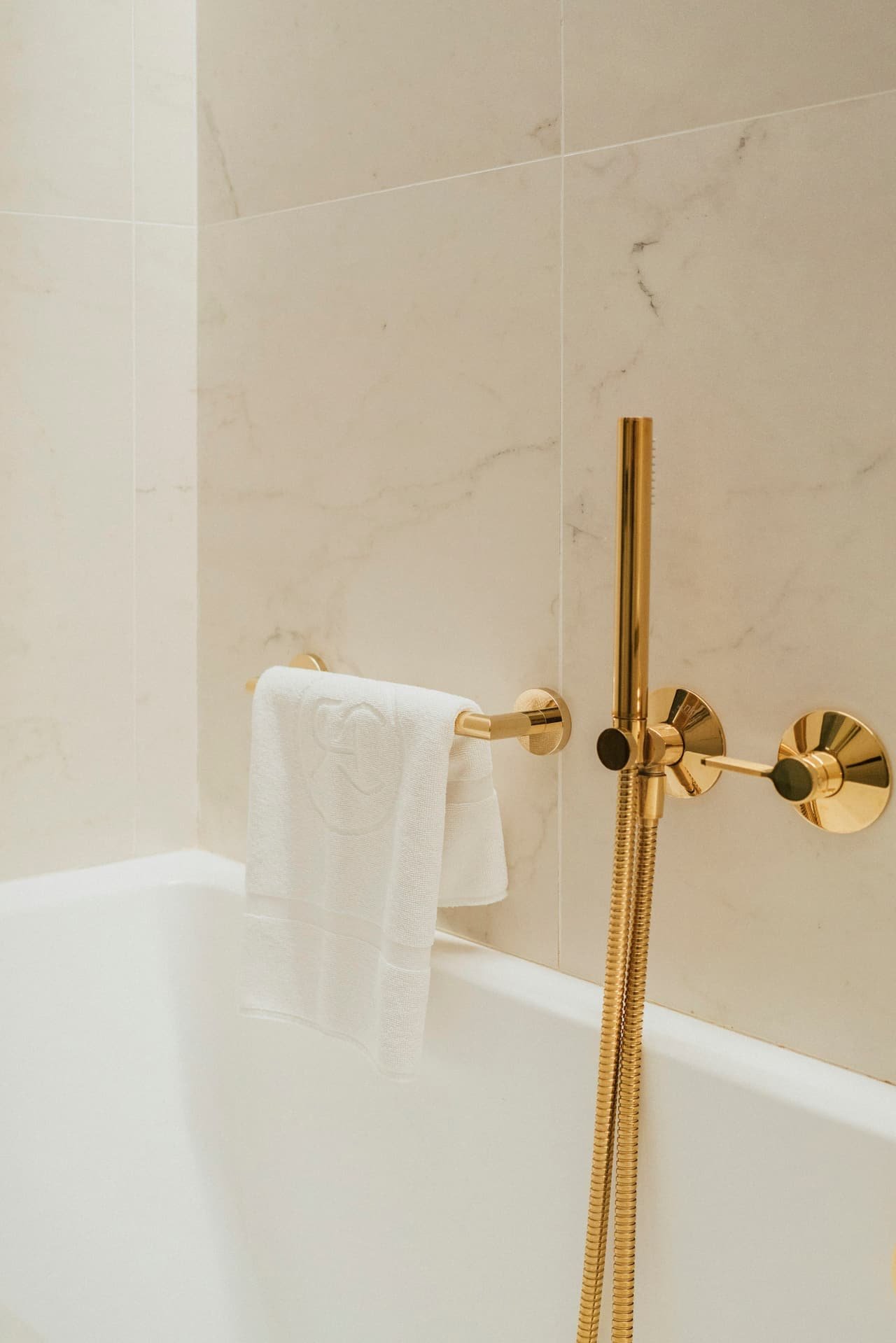 A white towel by brass bathroom fittings