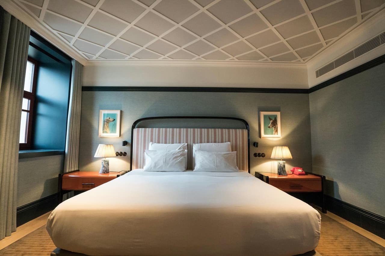 A bed under a patterned ceiling, with lamps on both sides