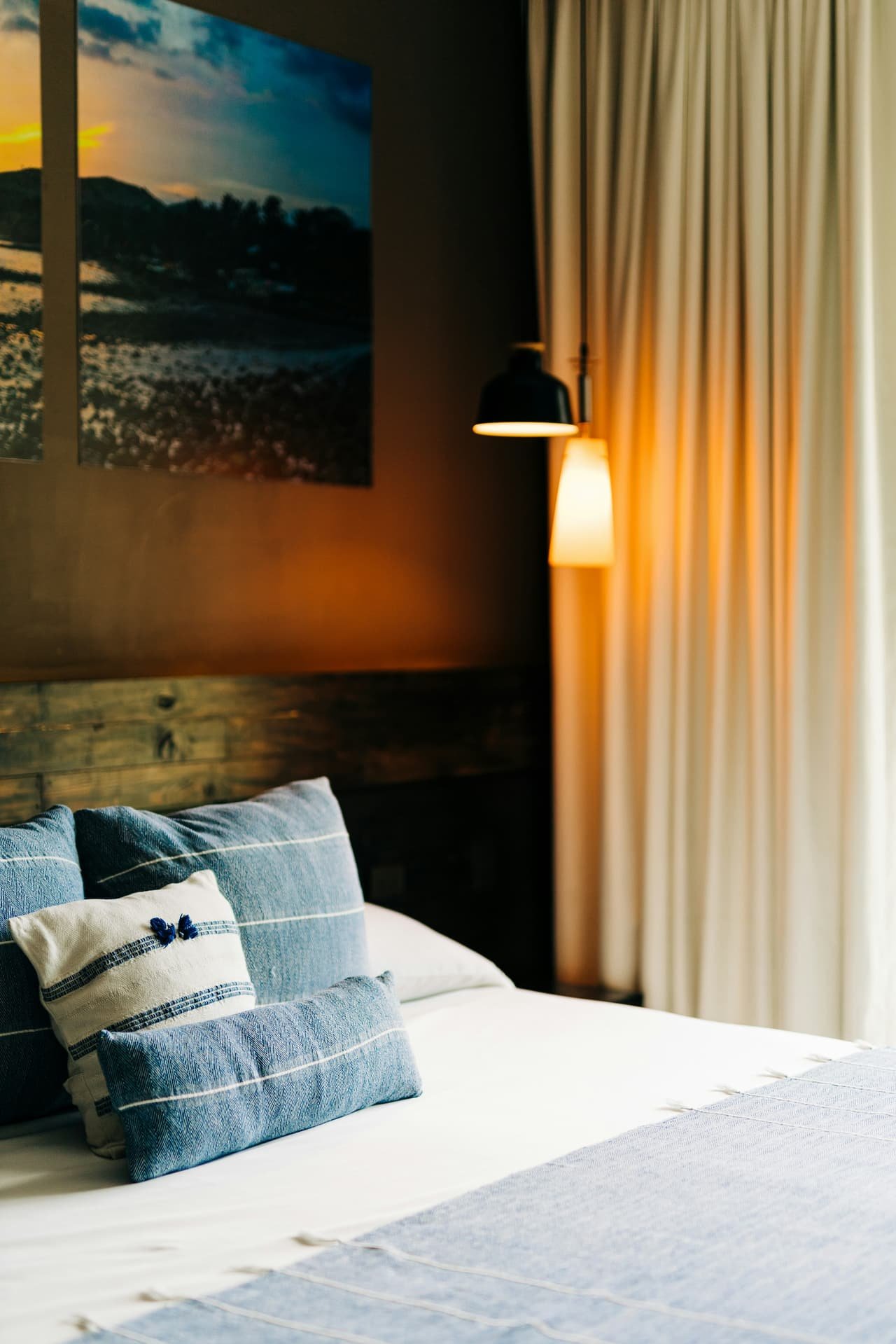 A bed with soft pillows under a framed painting