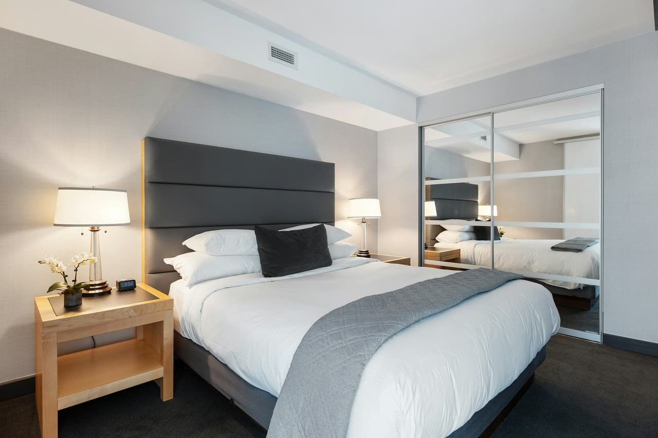 A king bed between warm bedside lamps, with a writing desk
