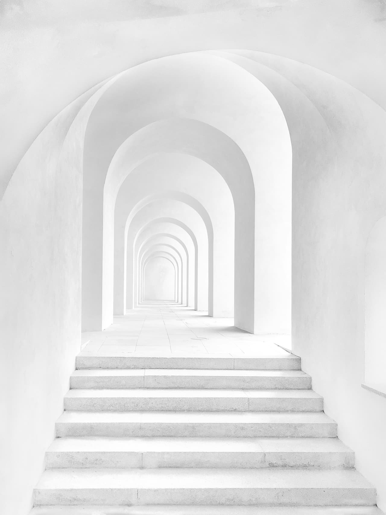 A white arched corridor with steps